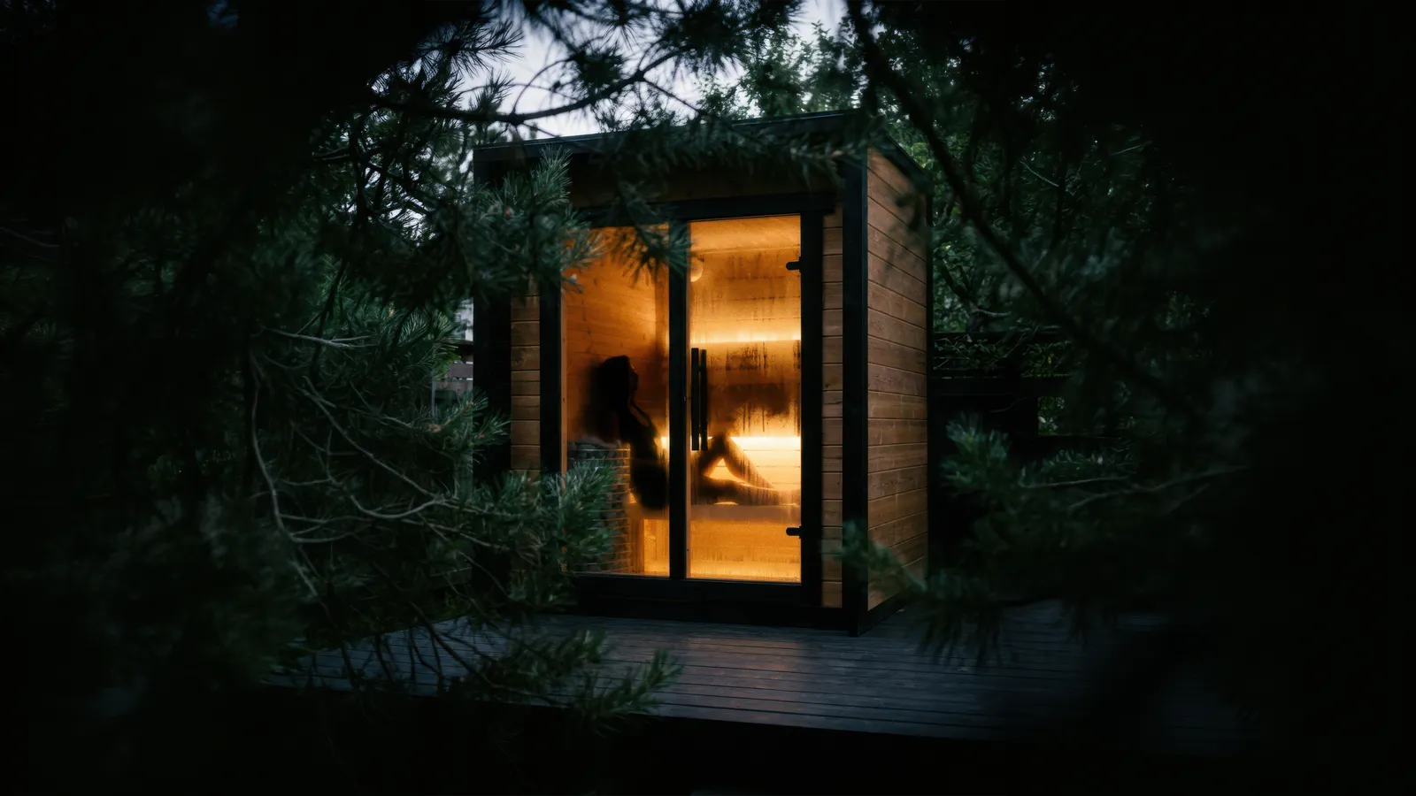 Sauna extérieur premium et sa baie vitrée, dans un jardin boisé